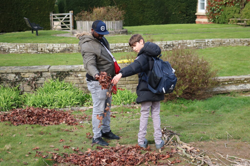 man and boy playing with dry leaves